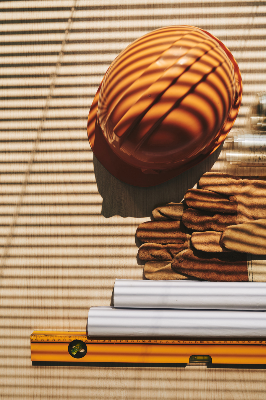 Hardhat, gloves and scrolls on table of engineer